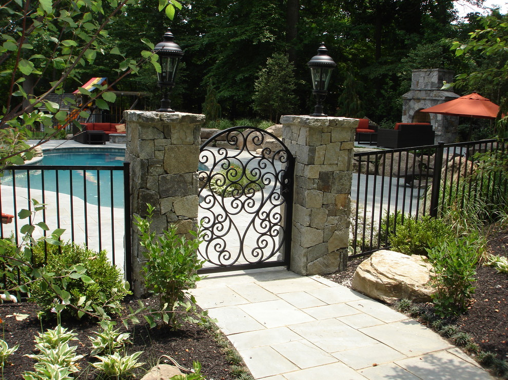 Diseño de piscina alargada tradicional grande a medida en patio trasero con adoquines de hormigón