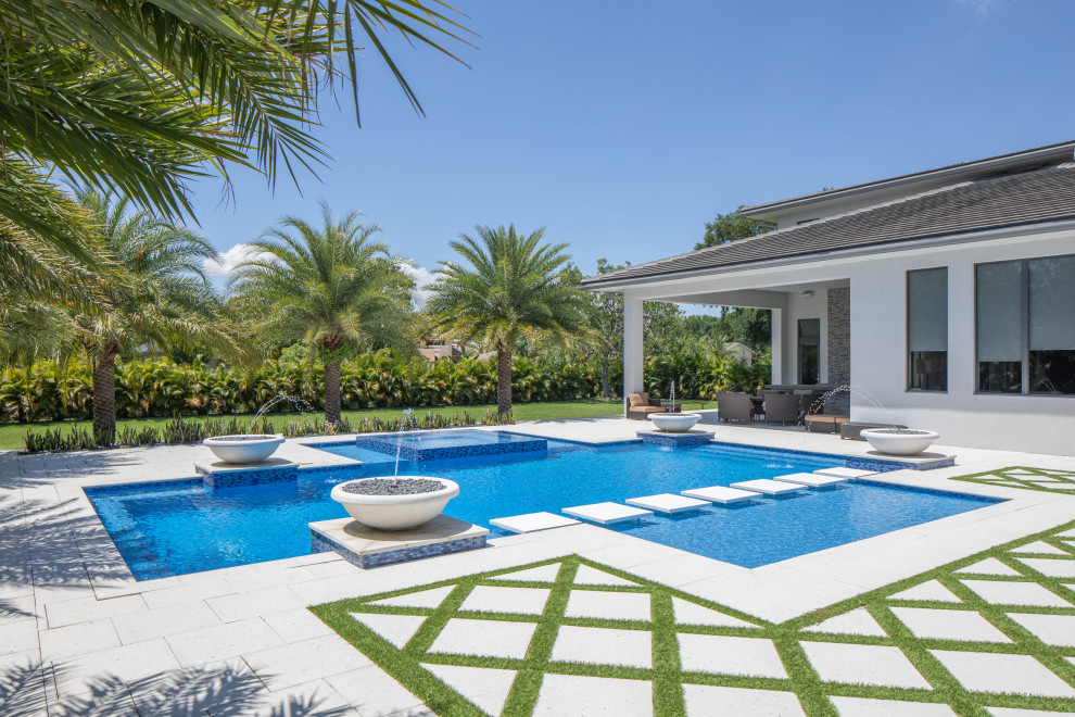 Foto di una grande piscina monocorsia minimalista personalizzata dietro casa con una vasca idromassaggio