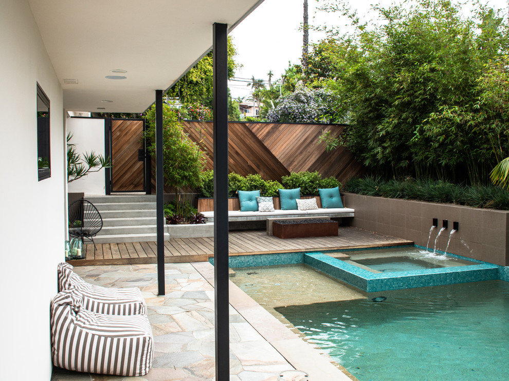 Foto di una grande piscina monocorsia minimal personalizzata in cortile con una vasca idromassaggio e pavimentazioni in pietra naturale