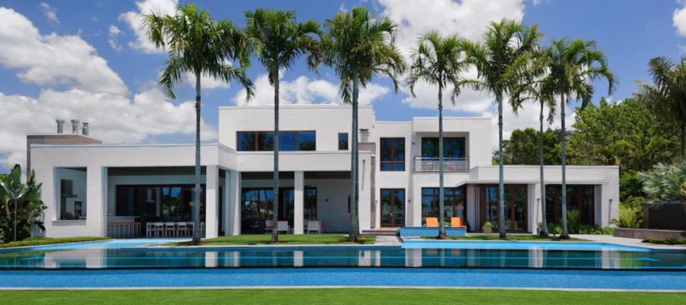 Esempio di una grande piscina monocorsia tropicale personalizzata dietro casa con fontane e lastre di cemento
