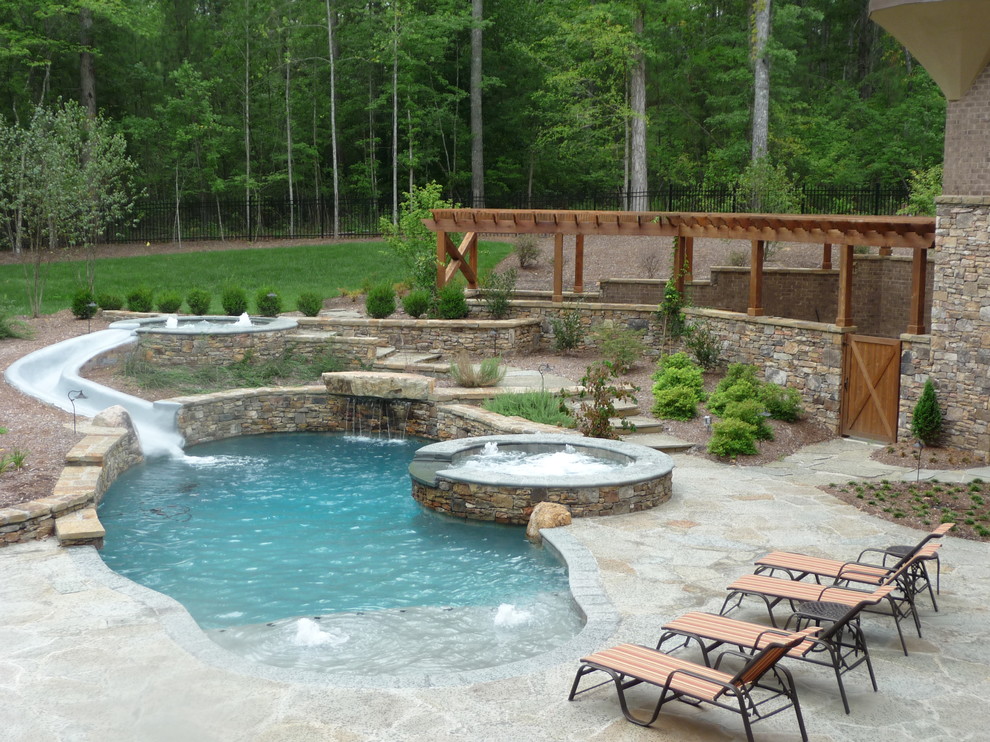 Idee per una piscina fuori terra stile americano rotonda dietro casa con un acquascivolo e pavimentazioni in pietra naturale