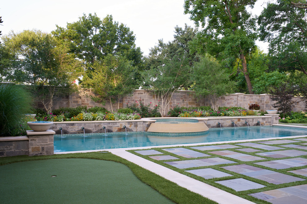 Réalisation d'une grande piscine tradition rectangle avec des pavés en pierre naturelle.