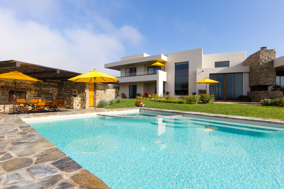 Foto på en stor funkis pool på baksidan av huset, med poolhus och naturstensplattor
