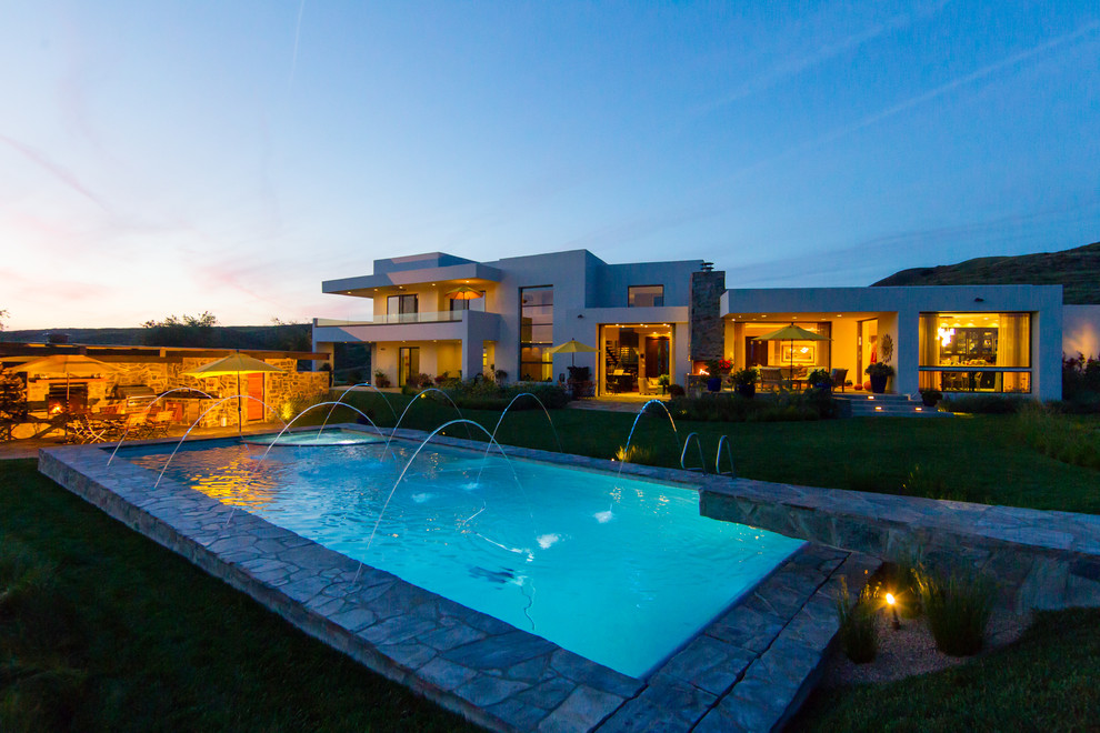 Photo of a large contemporary back rectangular swimming pool in San Luis Obispo with a pool house and natural stone paving.