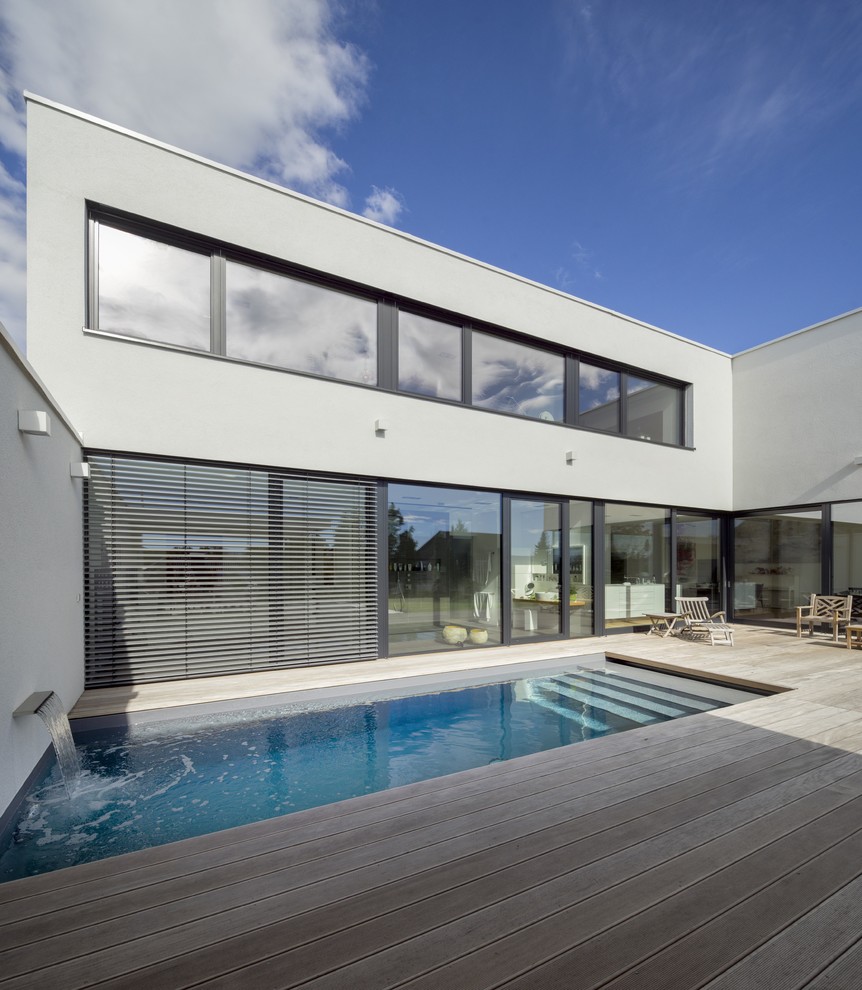 Cette photo montre une piscine moderne de taille moyenne et rectangle avec un point d'eau et une terrasse en bois.