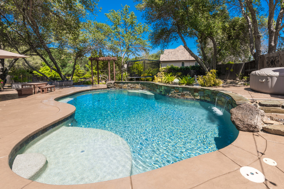Foto di una piscina tropicale personalizzata di medie dimensioni e dietro casa con fontane e pavimentazioni in pietra naturale