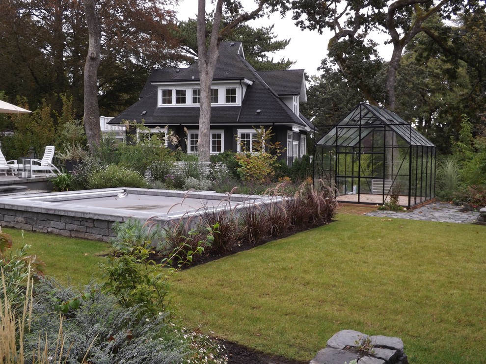 На фото: огромный прямоугольный бассейн на заднем дворе в классическом стиле с джакузи и покрытием из каменной брусчатки с