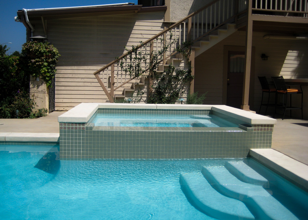 Ejemplo de piscinas y jacuzzis alargados modernos de tamaño medio en forma de L en patio trasero con losas de hormigón