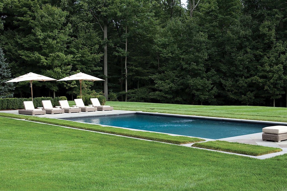 На фото: большой прямоугольный бассейн на заднем дворе в классическом стиле с покрытием из каменной брусчатки с