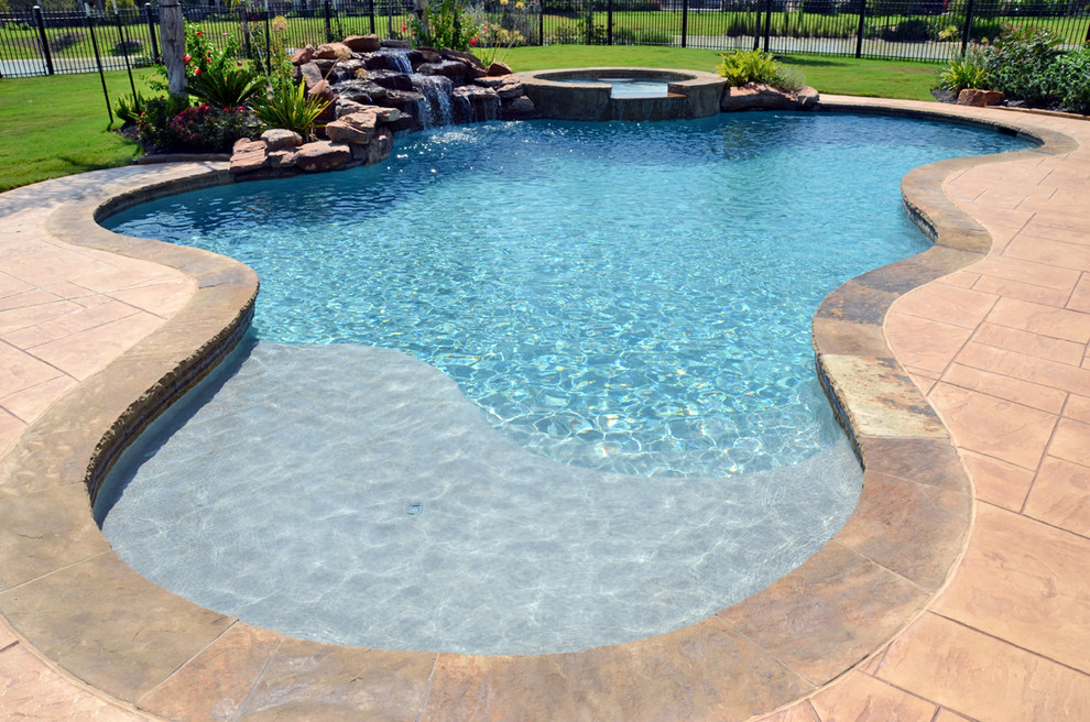 Imagen de piscina con fuente exótica grande a medida en patio trasero con suelo de baldosas