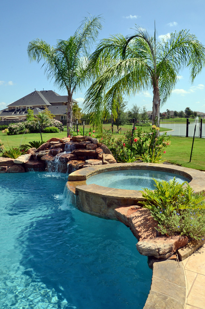 Photo of a large world-inspired back custom shaped swimming pool in Houston with tiled flooring and a water feature.