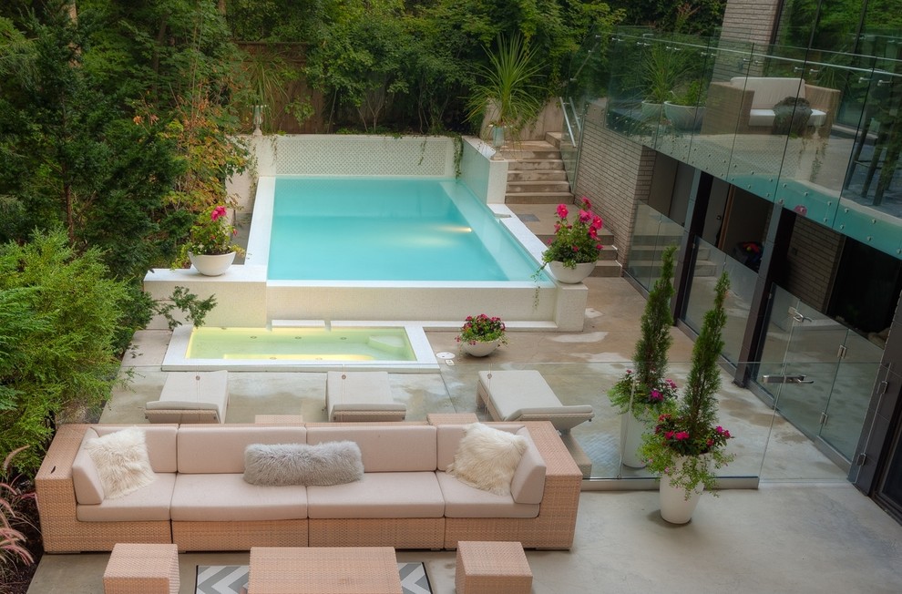 Modelo de piscinas y jacuzzis infinitos modernos pequeños rectangulares en patio trasero con suelo de hormigón estampado