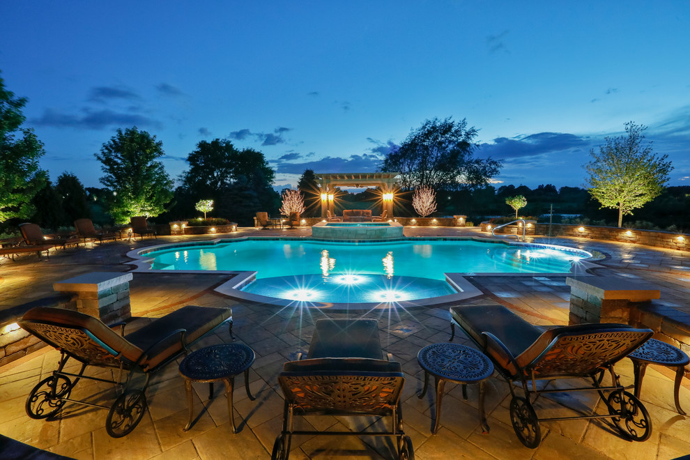 Example of a mid-sized tuscan backyard concrete paver and custom-shaped lap hot tub design in Chicago