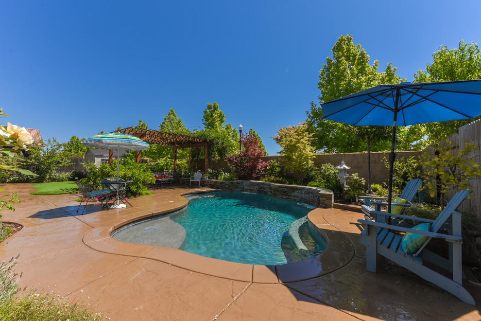 Mittelgroßer Pool hinter dem Haus in individueller Form mit Wasserspiel und Natursteinplatten in Sacramento