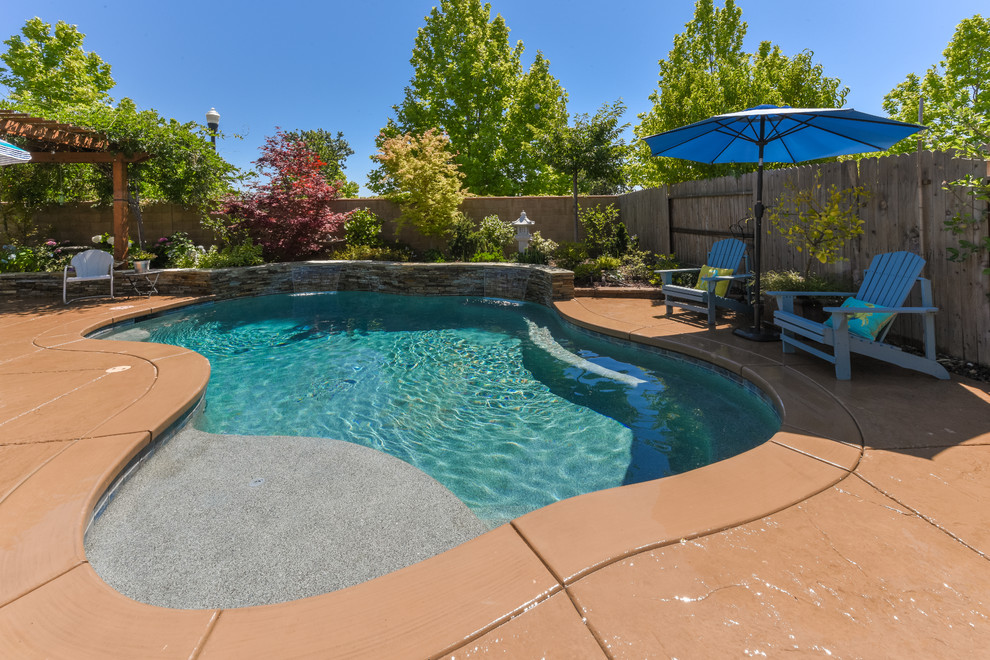 Mittelgroßer Pool hinter dem Haus in individueller Form mit Wasserspiel und Natursteinplatten in Sacramento