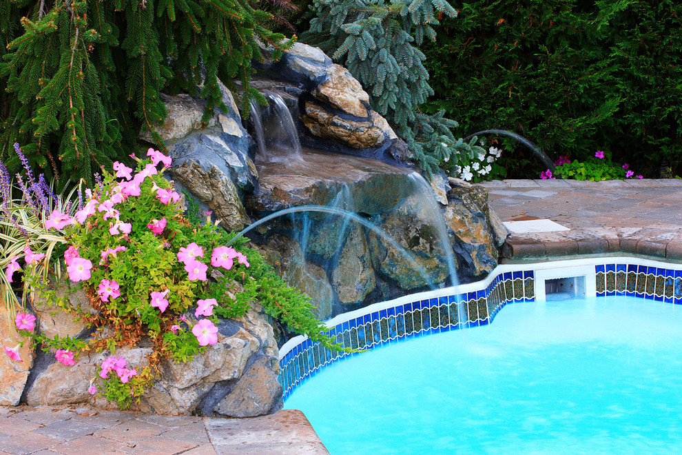 Diseño de piscina con fuente tradicional renovada de tamaño medio a medida en patio trasero con adoquines de ladrillo