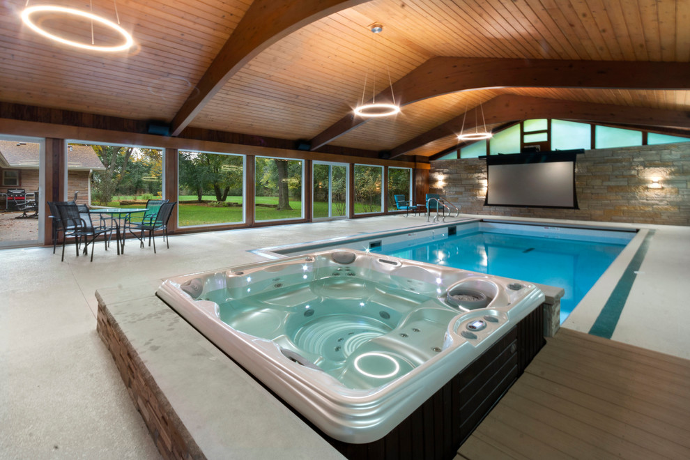 Ispirazione per una piccola piscina coperta moderna rettangolare con una vasca idromassaggio e lastre di cemento