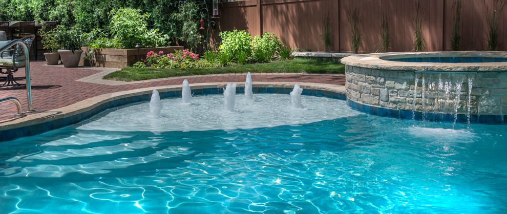 Modelo de piscinas y jacuzzis naturales de tamaño medio a medida en patio trasero con adoquines de ladrillo
