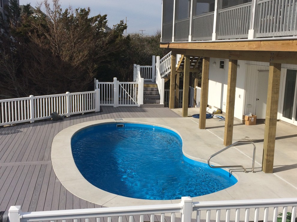 Idee per una piscina stile marino a "C" di medie dimensioni e dietro casa con lastre di cemento