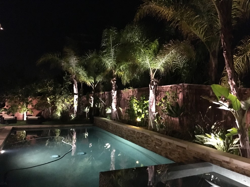 This is an example of a large traditional back rectangular lengths swimming pool in San Diego with natural stone paving.