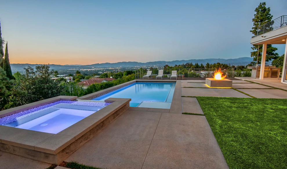 Idee per una piscina design rettangolare di medie dimensioni e dietro casa con lastre di cemento e una vasca idromassaggio