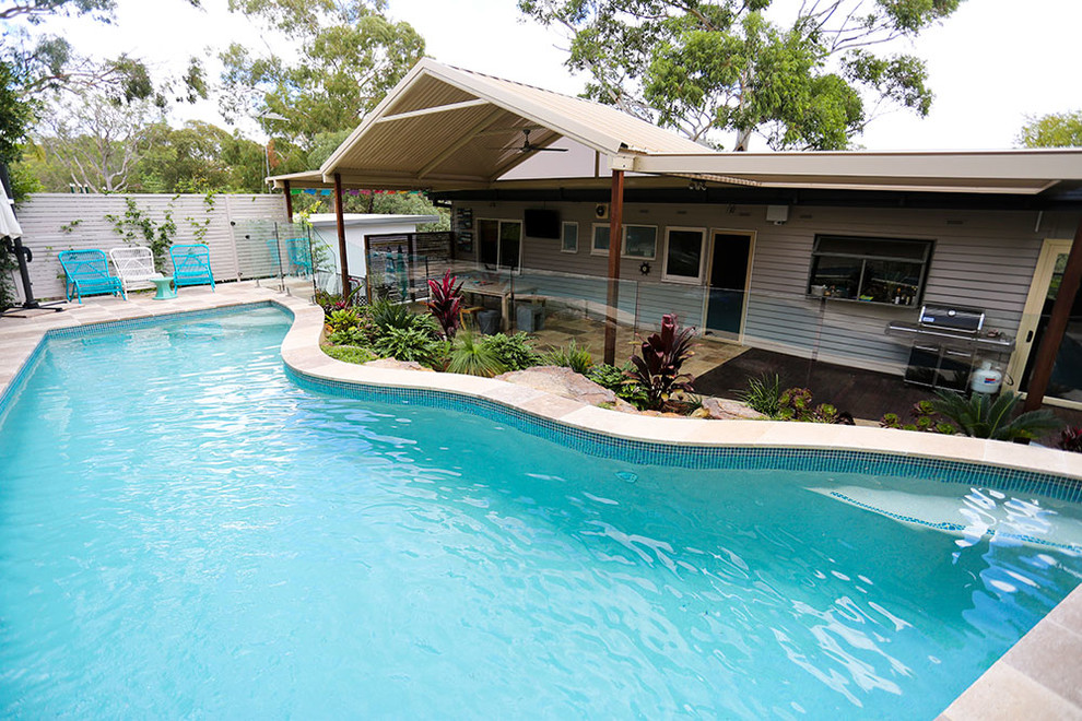 Inspiration för en mellanstor funkis anpassad pool på baksidan av huset, med naturstensplattor