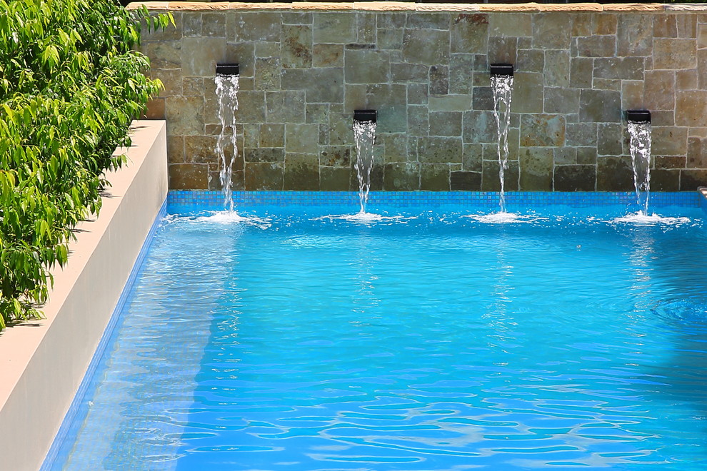 Esempio di una grande piscina monocorsia design rettangolare dietro casa con un acquascivolo e pavimentazioni in pietra naturale