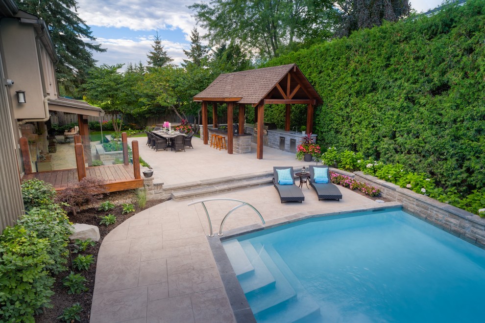Modelo de casa de la piscina y piscina alargada actual grande rectangular en patio trasero con suelo de hormigón estampado
