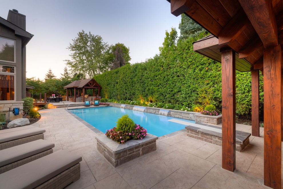 Large trendy backyard stamped concrete and rectangular lap pool house photo in Toronto