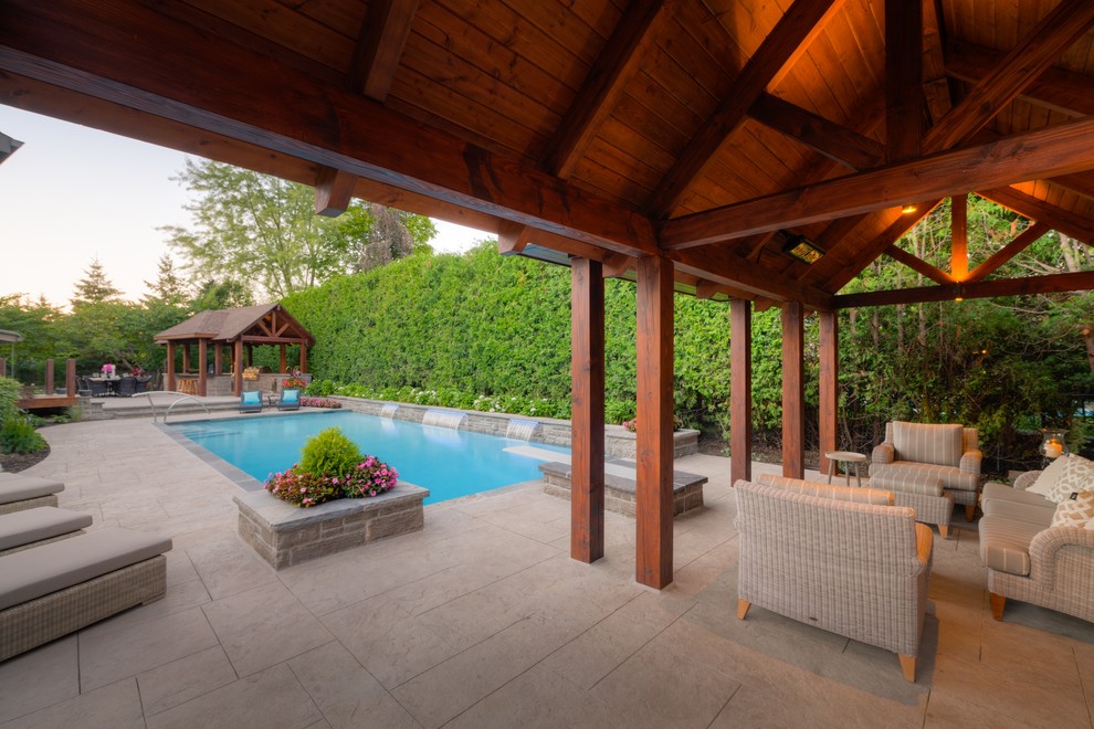 Ejemplo de casa de la piscina y piscina alargada contemporánea grande rectangular en patio trasero con suelo de hormigón estampado