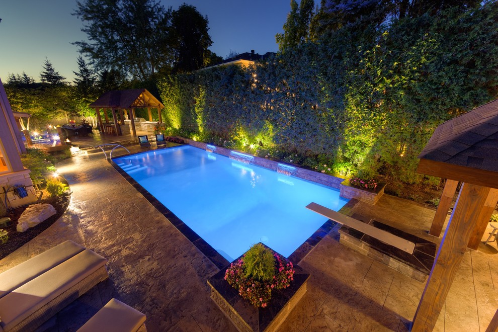 Diseño de casa de la piscina y piscina alargada contemporánea grande rectangular en patio trasero con suelo de hormigón estampado