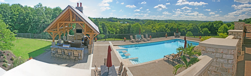 Ejemplo de casa de la piscina y piscina actual extra grande rectangular en patio trasero con losas de hormigón