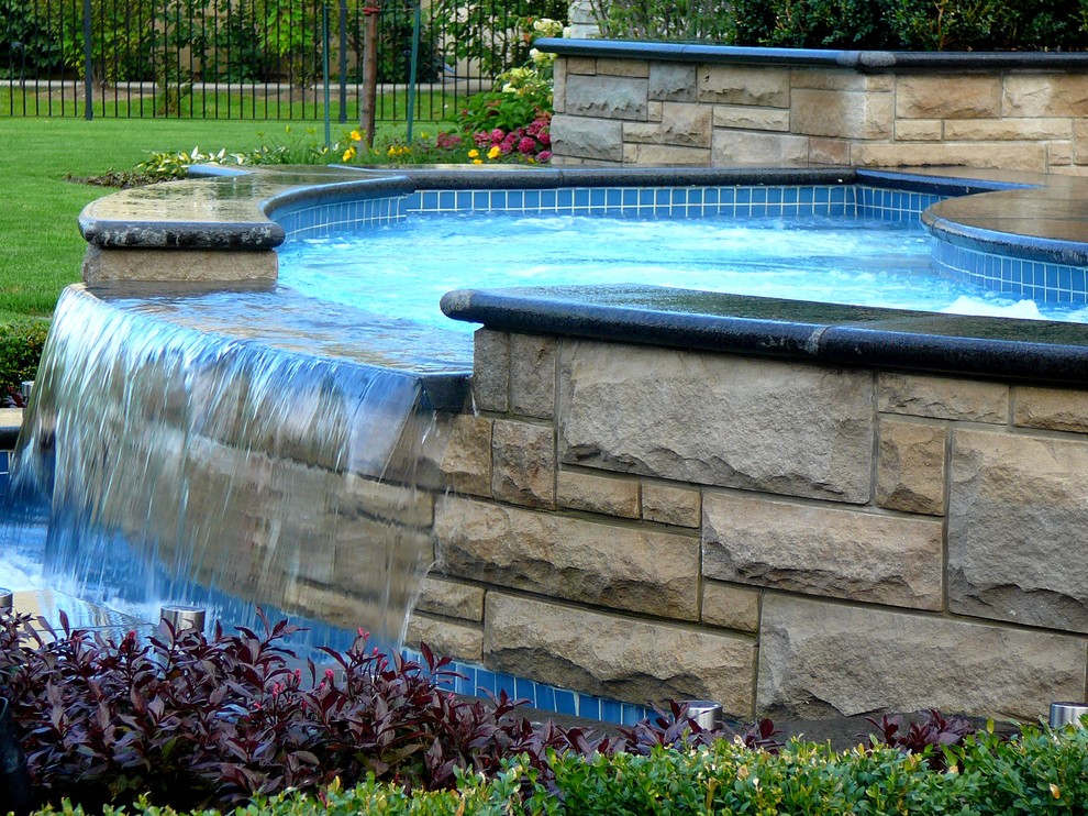 Cette photo montre une piscine arrière tendance sur mesure avec un bain bouillonnant et des pavés en pierre naturelle.