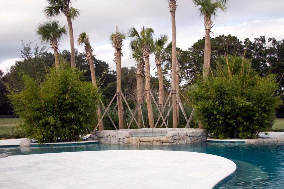 Réalisation d'une piscine arrière méditerranéenne de taille moyenne et sur mesure avec une dalle de béton et un bain bouillonnant.