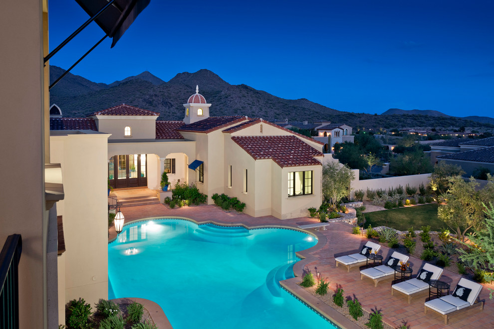 Diseño de piscina con fuente elevada mediterránea grande a medida en patio trasero con adoquines de ladrillo