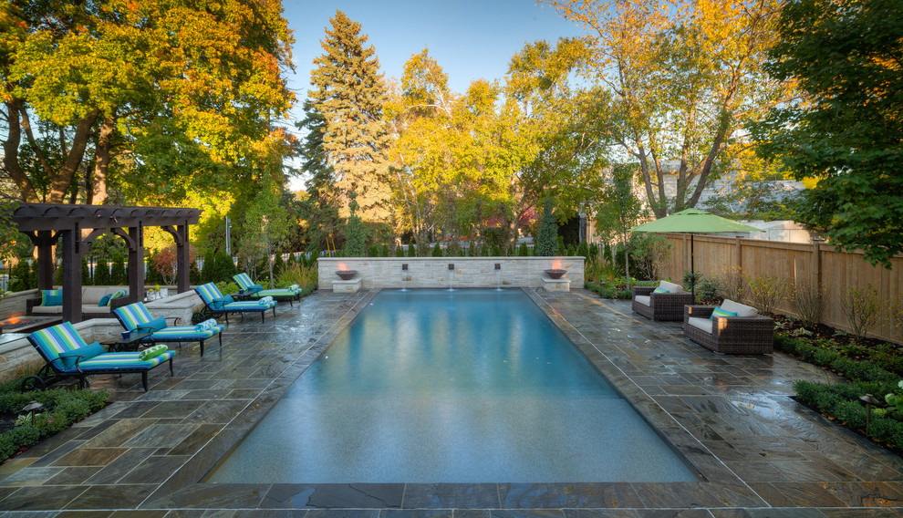 Ispirazione per una grande piscina chic rettangolare dietro casa con fontane e pavimentazioni in pietra naturale
