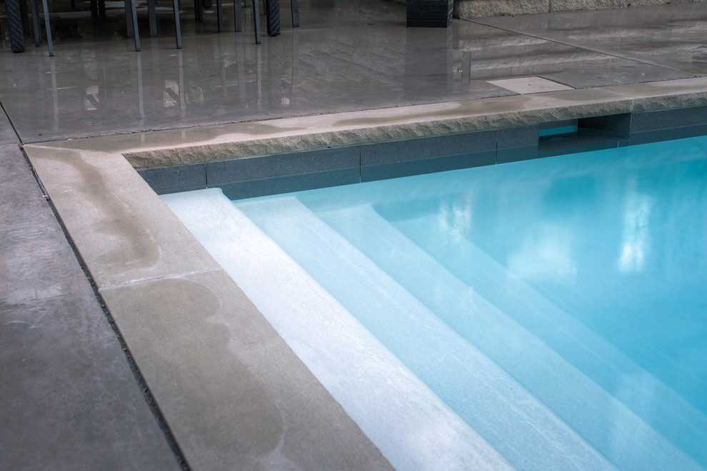 Idées déco pour une grande piscine arrière classique rectangle avec un bain bouillonnant et une dalle de béton.