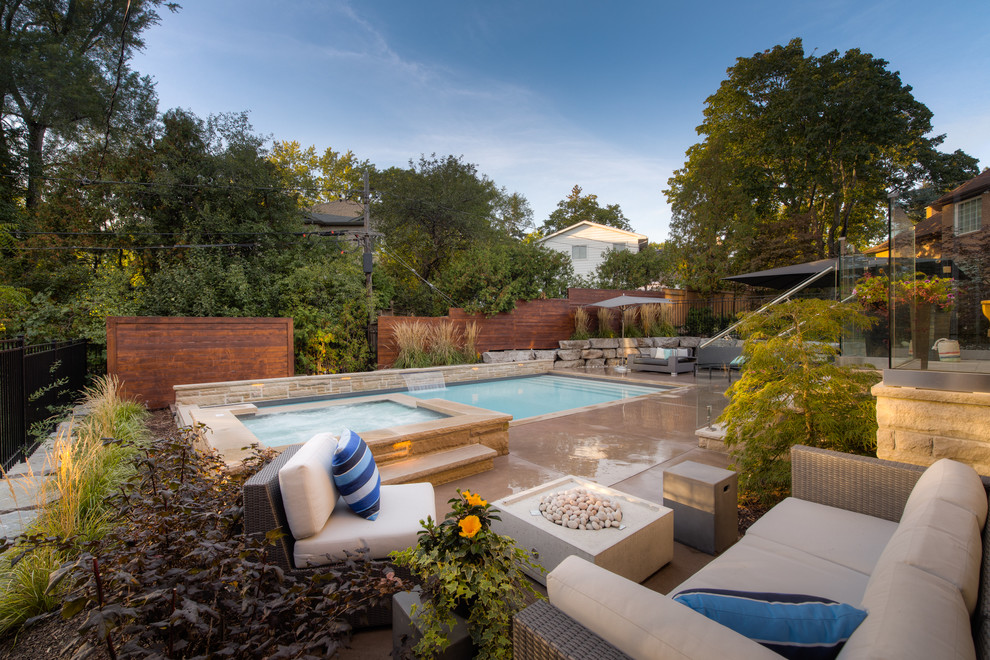 Пример оригинального дизайна: большой прямоугольный бассейн на заднем дворе в стиле неоклассика (современная классика) с джакузи и покрытием из бетонных плит