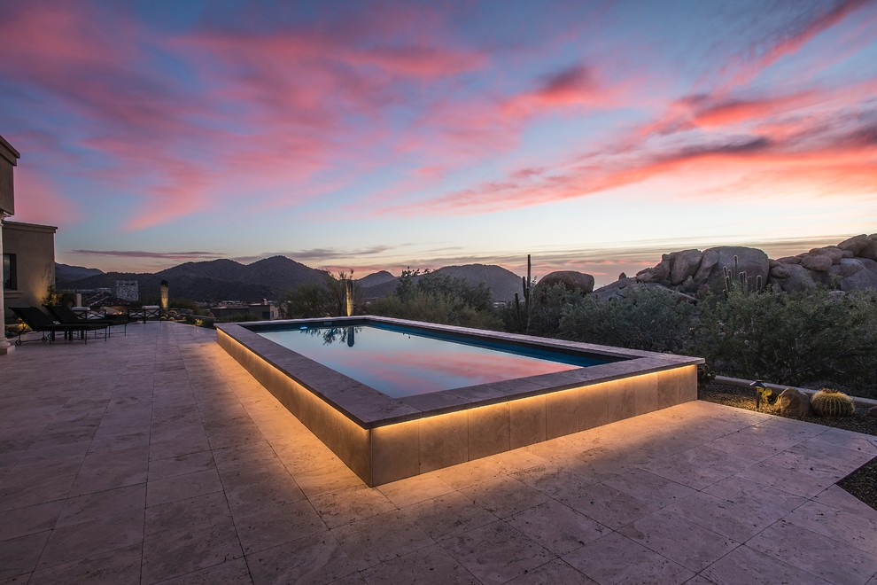 Modelo de piscina alargada clásica renovada de tamaño medio rectangular en patio trasero con adoquines de piedra natural