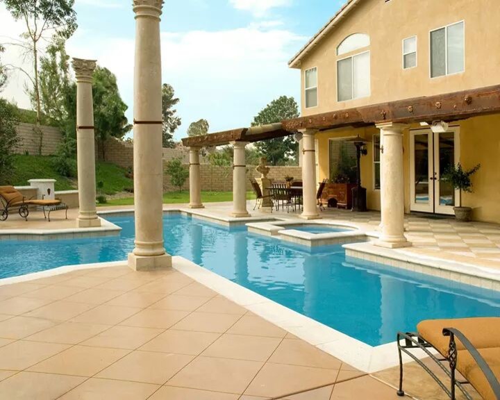 Ejemplo de piscina con fuente natural retro grande a medida en patio trasero con losas de hormigón