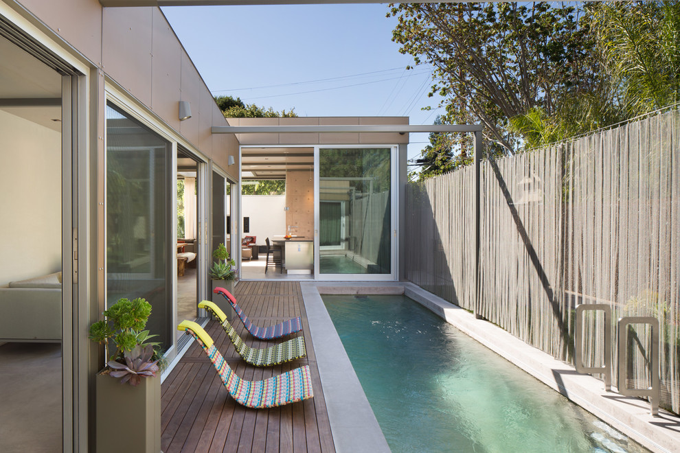 Идея дизайна: большой прямоугольный бассейн-инфинити на заднем дворе в современном стиле с настилом
