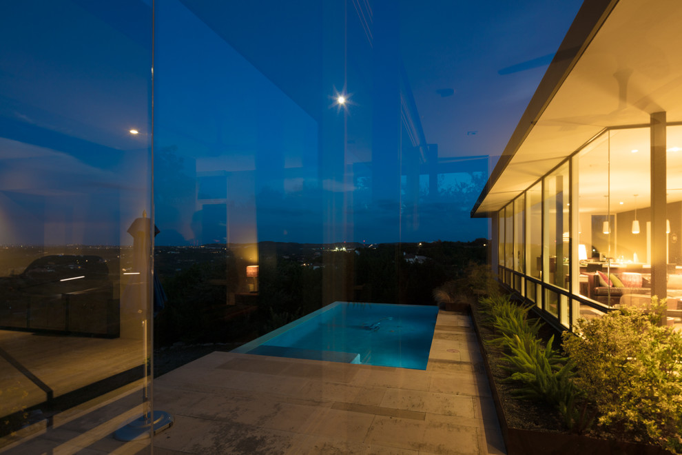 Foto de piscina infinita minimalista de tamaño medio rectangular en patio lateral con adoquines de piedra natural