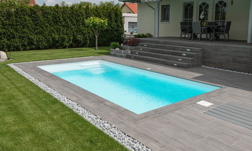 Imagen de piscina contemporánea rectangular en patio trasero con suelo de baldosas
