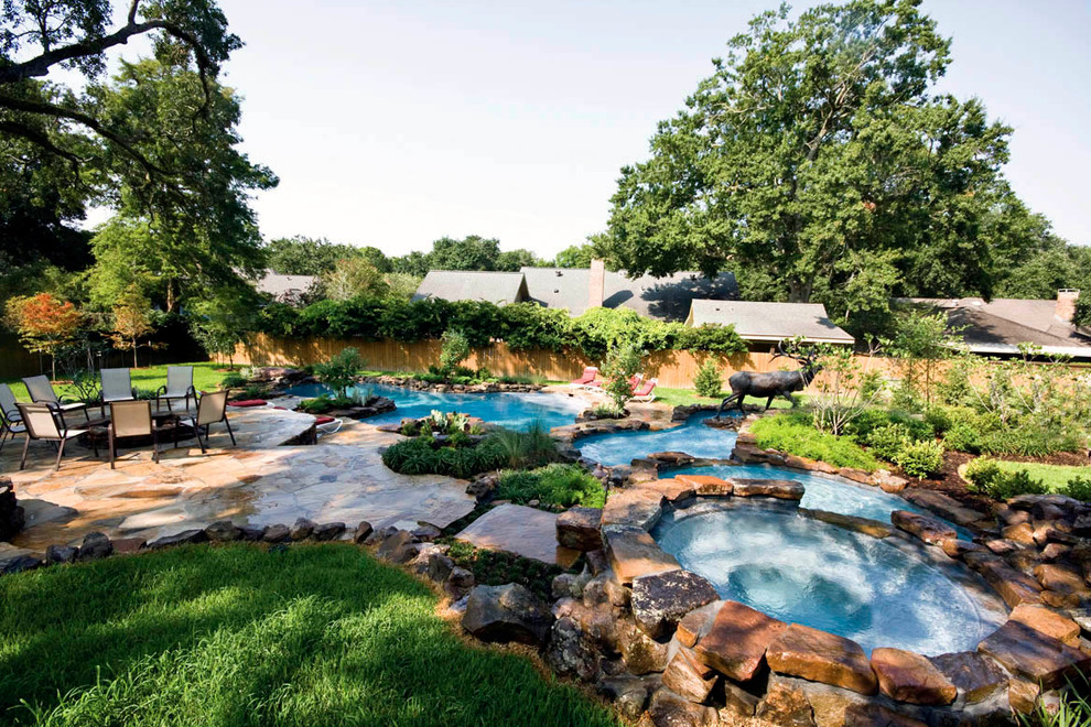 На фото: естественный бассейн произвольной формы, среднего размера на заднем дворе в современном стиле с покрытием из каменной брусчатки и джакузи