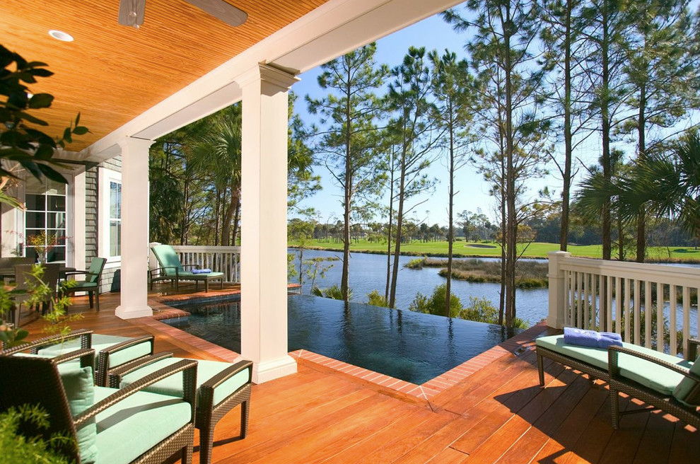 Cette photo montre une piscine à débordement et arrière bord de mer de taille moyenne et rectangle avec une terrasse en bois.