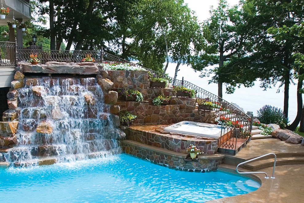 Foto de piscinas y jacuzzis elevados tropicales grandes rectangulares en patio trasero con adoquines de piedra natural