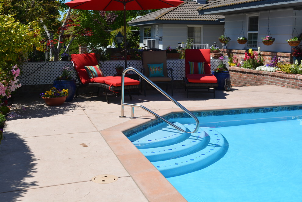 Photo of a large traditional side custom shaped swimming pool in Sacramento with stamped concrete.