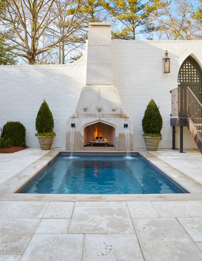 Ejemplo de piscina con fuente de tamaño medio rectangular en patio trasero con adoquines de hormigón