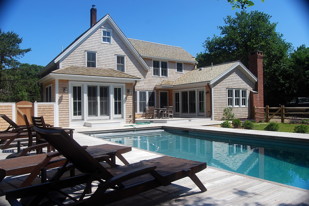 Diseño de piscina alargada clásica grande rectangular en patio trasero con entablado