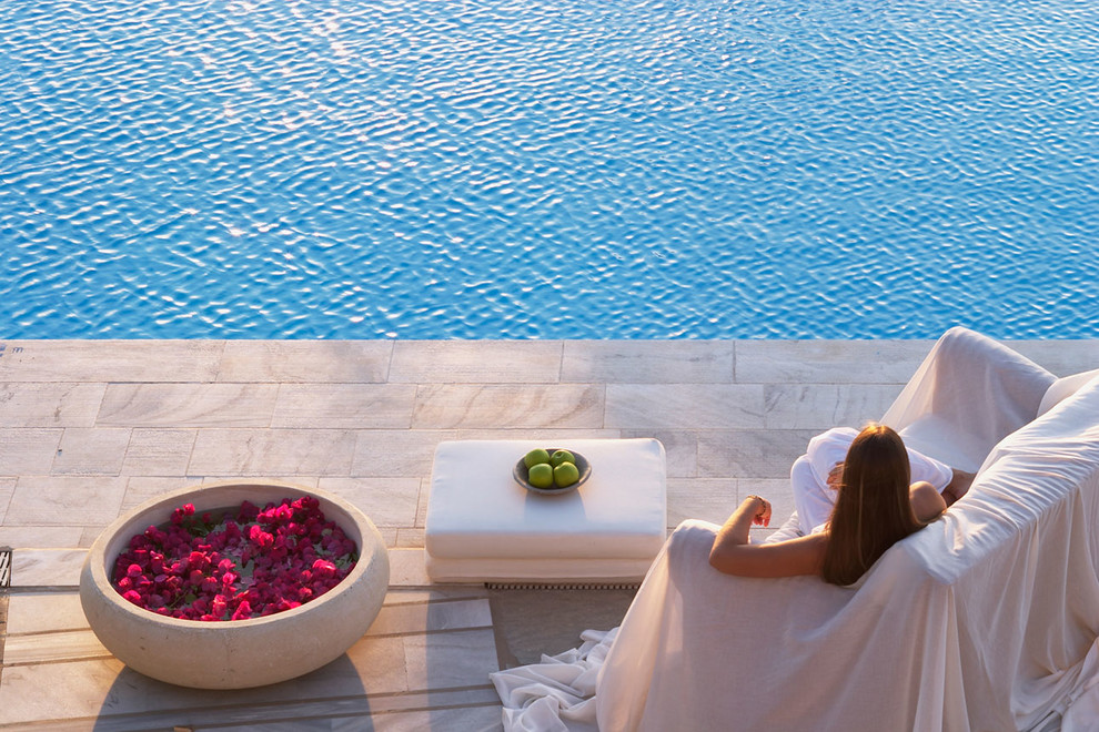 Ejemplo de piscina natural mediterránea grande rectangular en patio trasero con adoquines de piedra natural